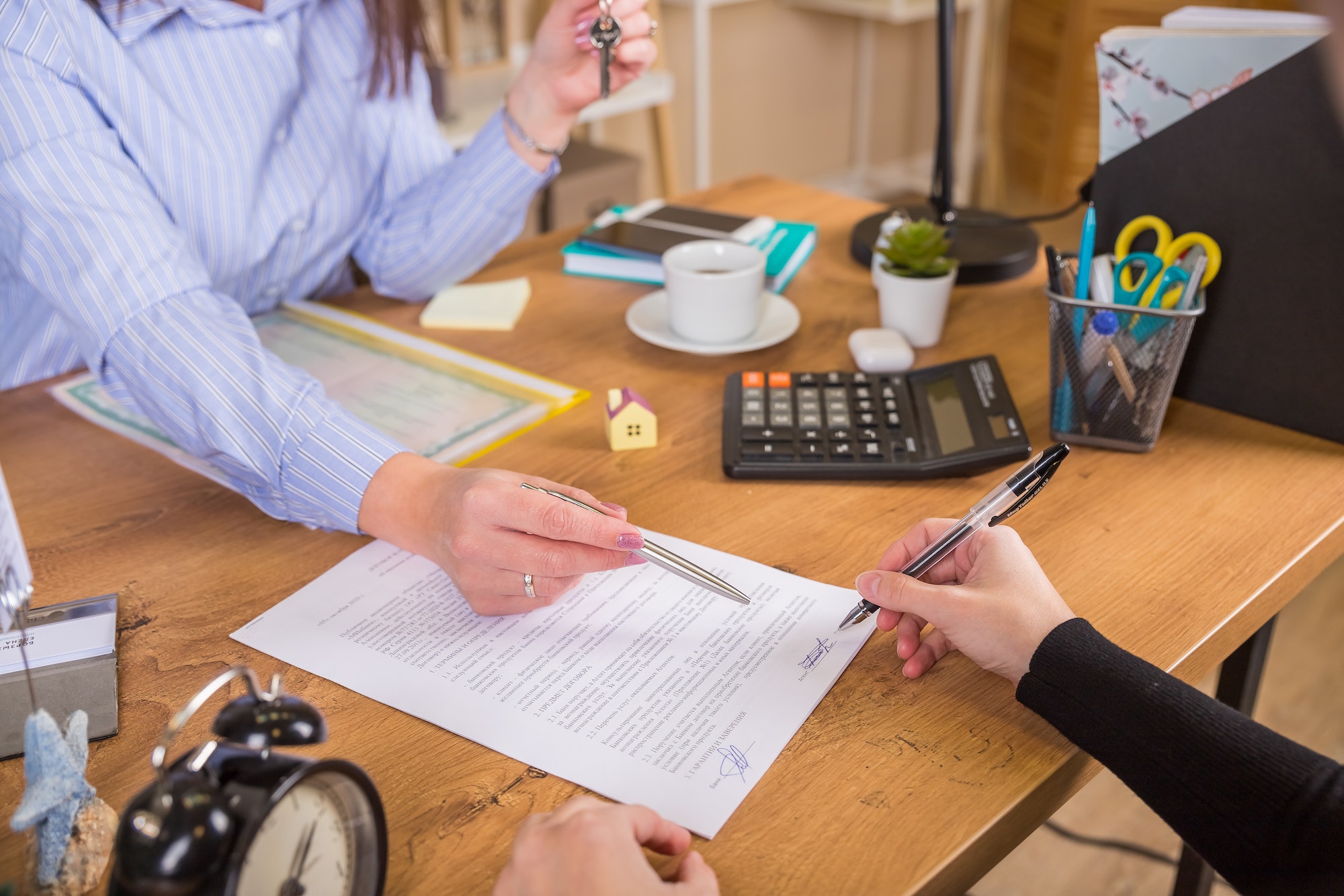 Client signs document regarding real estate activity next to lawyer or real estate agent sitting at